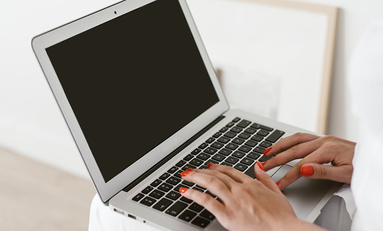 Woman Working With Laptop On Knees