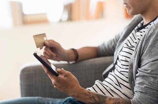 man shopping on mobile device at home holding credit card