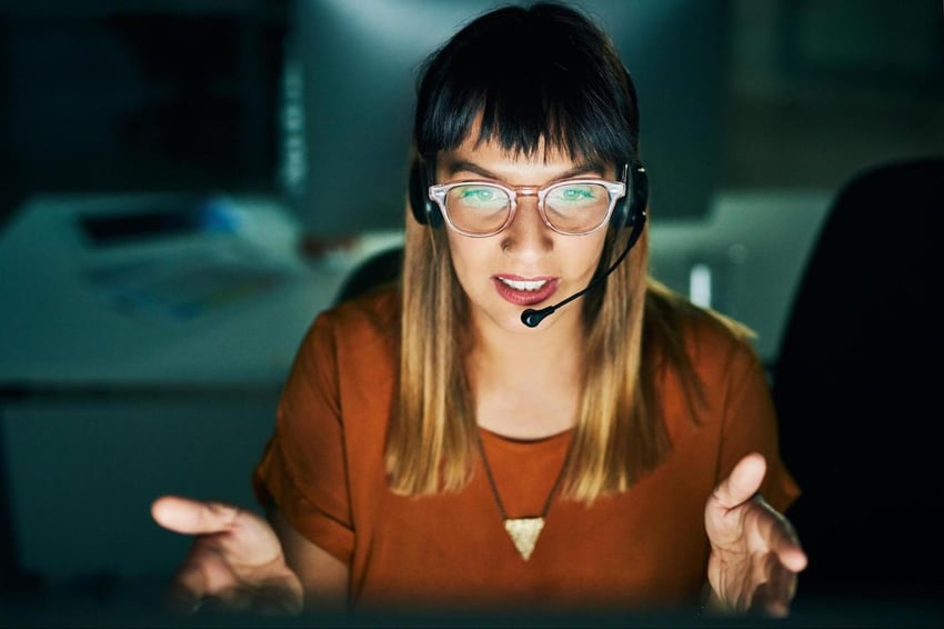 contact centre agent gestures while talking in darkened office