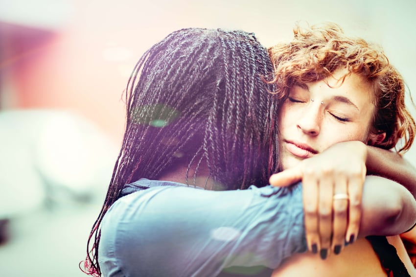 African woman supporting her Caucasian girlfriend, outdoors.