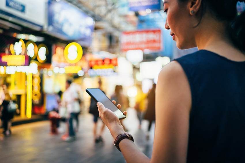 Woman with phone standing in front of stores