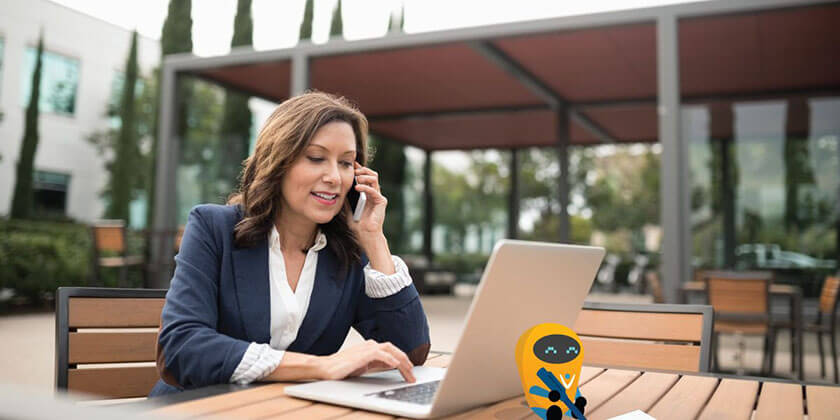 Photo of a woman talking on the phone and working on a computer. 