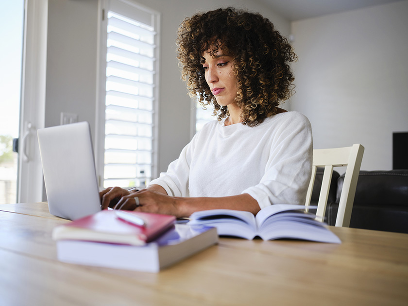 Student with school books open looking at laptop computer